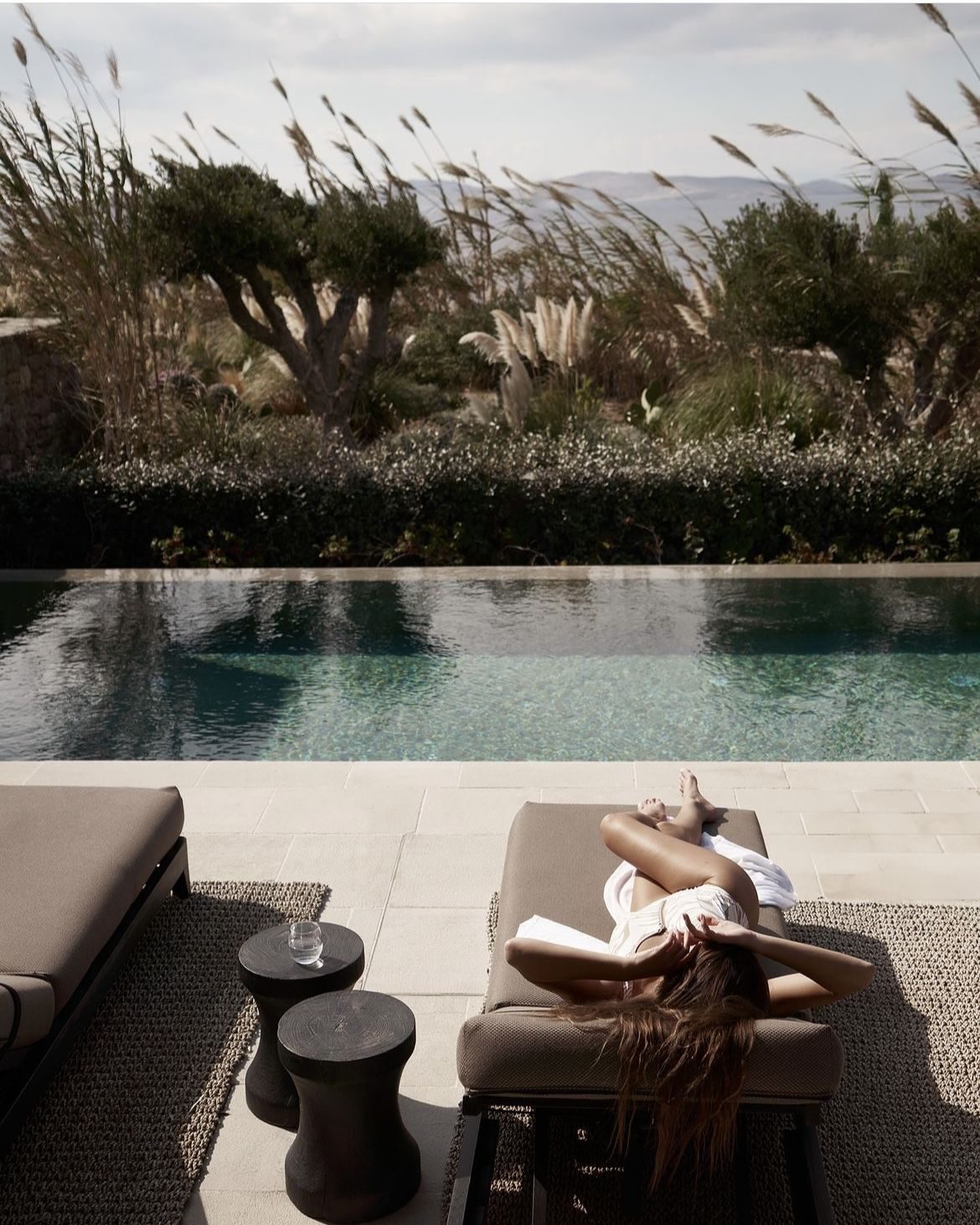 Guest unwinding beside a grass-fringed infinity pool