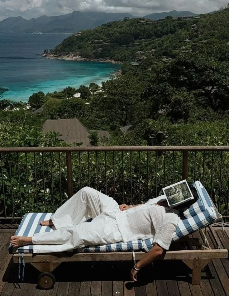 Creator resting on a striped lounger above the coast